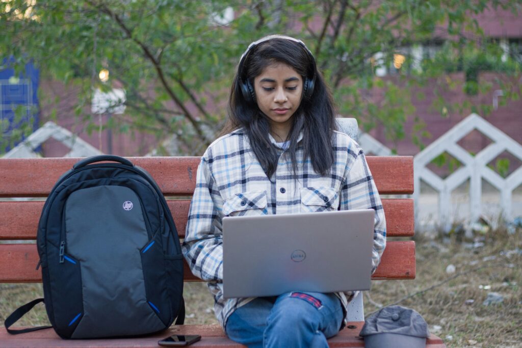 a girl sitting on a bench using a laptop working on a 12 day scholarship sprint