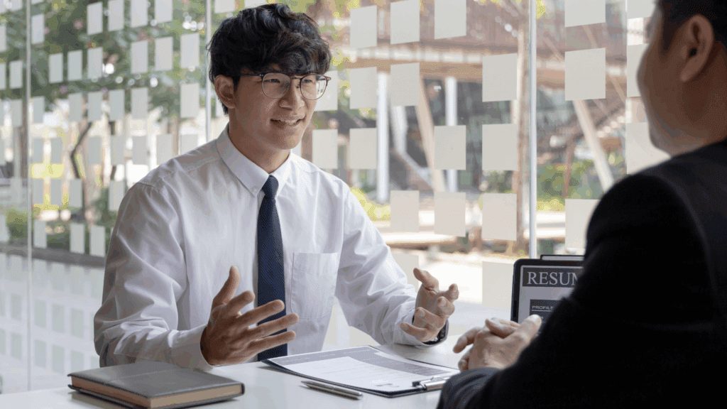 First-generation college student in a job interview discussing a paid winter internship, with a resume on the table.