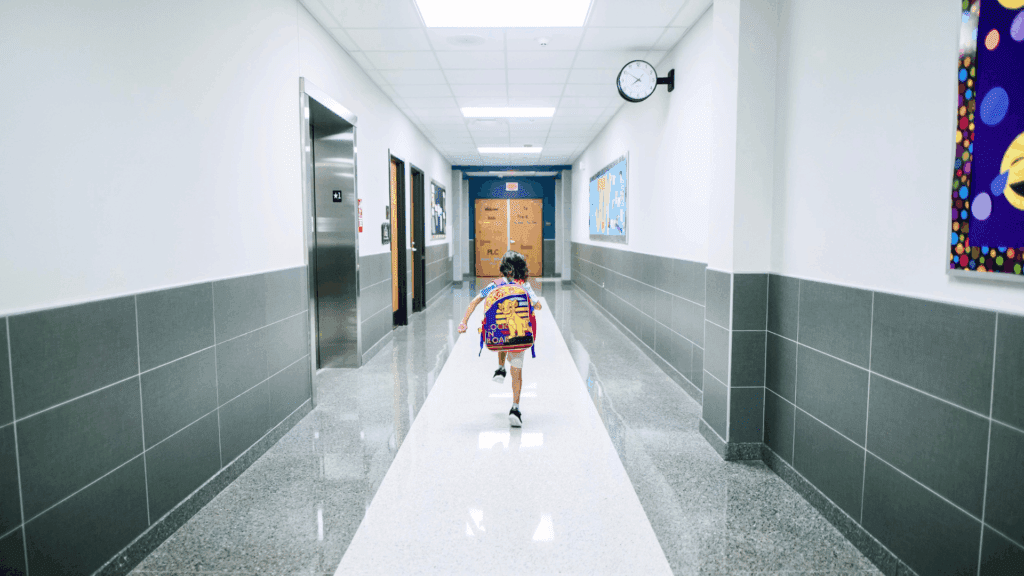 Young student with a backpack running down a bright school hallway, emphasizing attendance and reliable transportation.
