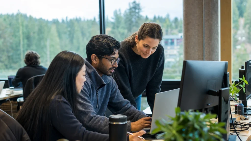 Software engineering volunteers collaborating on iLevelUP application development in a bright workspace.