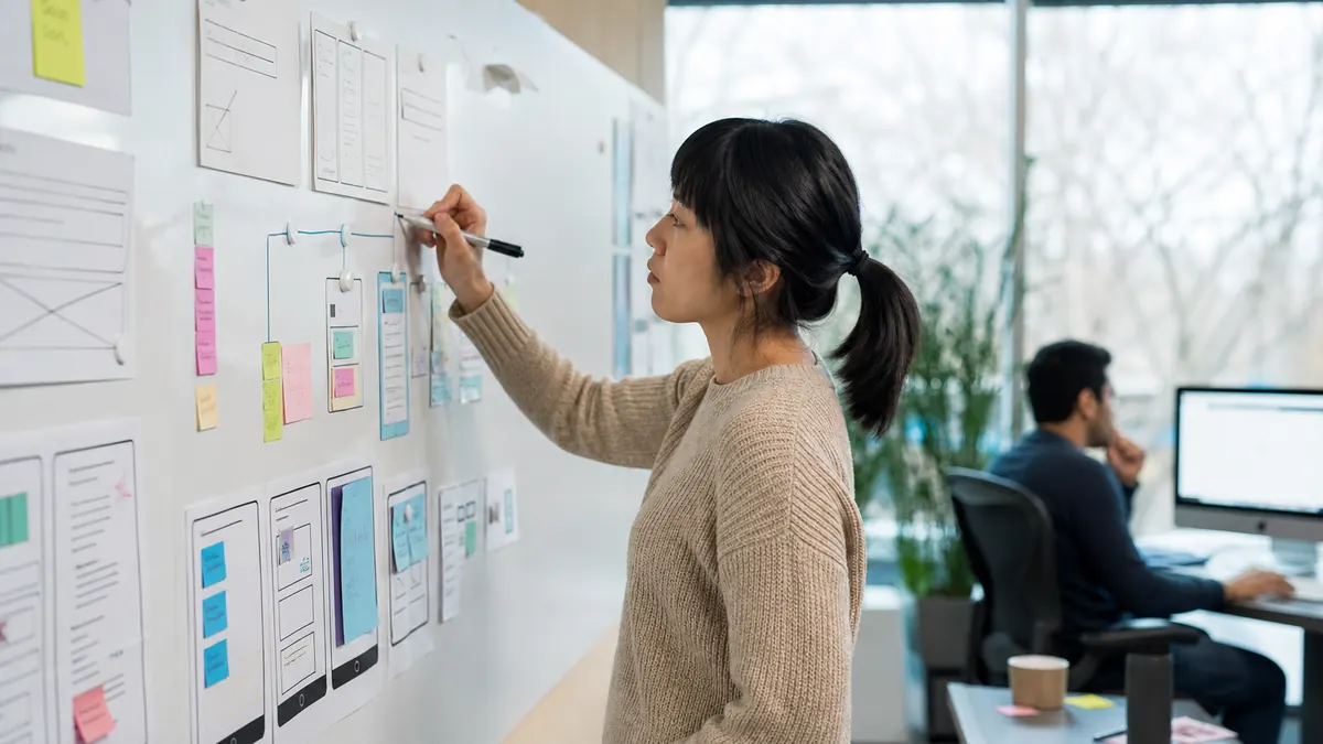 UX Designer volunteer mapping an accessible learning journey with abstract wireframes and interaction cards without readable text or student data.