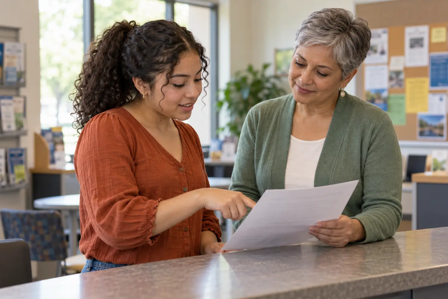 A student and adviser discuss high school resume skills while reviewing a printed resume at a community career center.